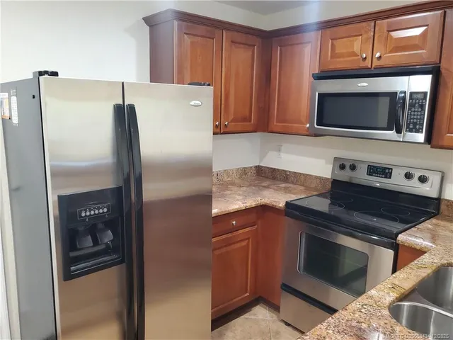 a kitchen with stainless steel appliances granite countertop a stove a sink dishwasher a refrigerator and a microwave