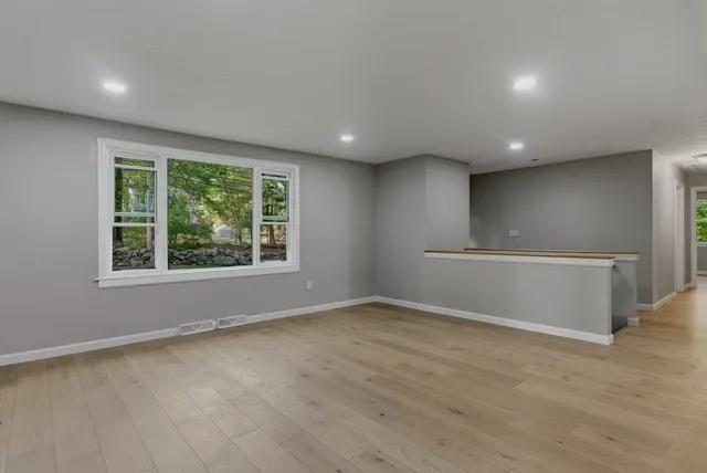 a living room with stainless steel appliances kitchen island hardwood floor and a window