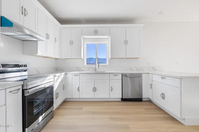 a kitchen with granite countertop a sink a stove and cabinets