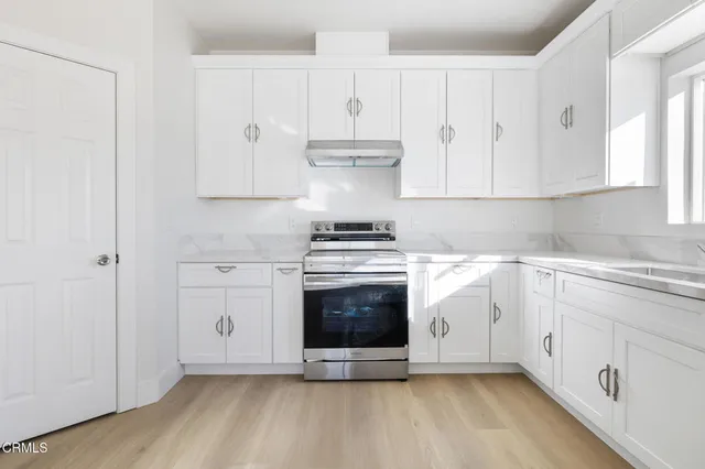 a kitchen with granite countertop white cabinets and stainless steel appliances