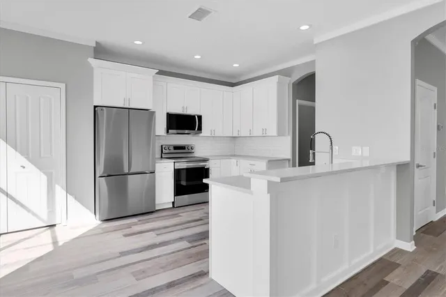 a kitchen with a refrigerator stove and white cabinets