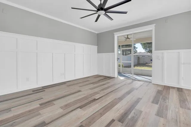 an empty room with wooden floor and a ceiling fan