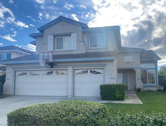 a view of a house with a yard and a large tree