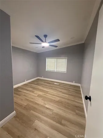 a view of empty room with wooden floor and fan