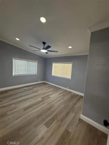 a view of empty room with wooden floor and fan
