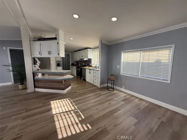 a living room with hard wood floors and a kitchen