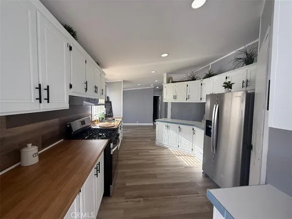 a kitchen with stainless steel appliances a refrigerator sink and wooden floor