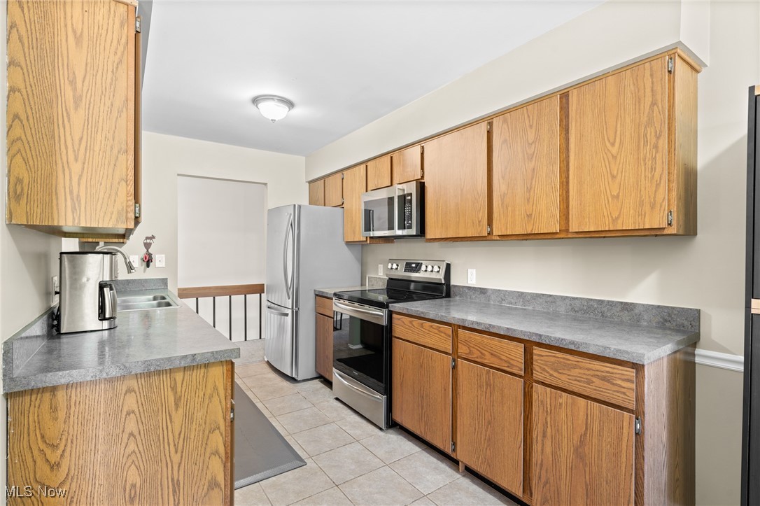 889 Hampton Ridge Drive Akron, OH 44313 - Photo 20 of 38 Kitchen featuring light tile patterned floors, stainless steel appliances, and sink