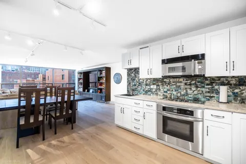 a kitchen with stainless steel appliances kitchen island granite countertop a stove top oven a sink a dining table and chairs