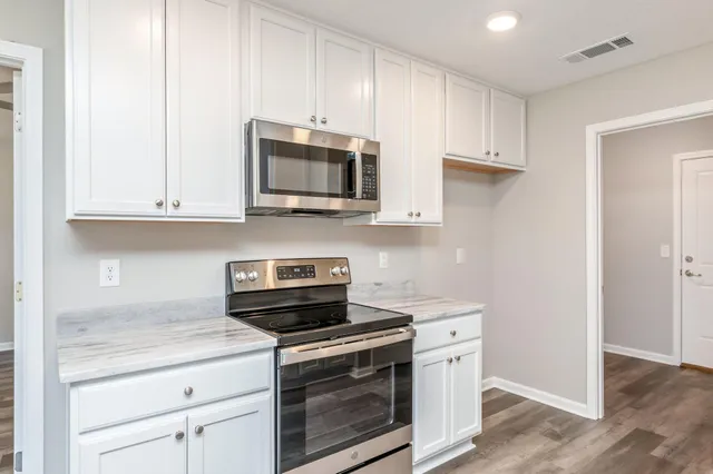 a kitchen with stainless steel appliances granite countertop white cabinets a sink and dishwasher