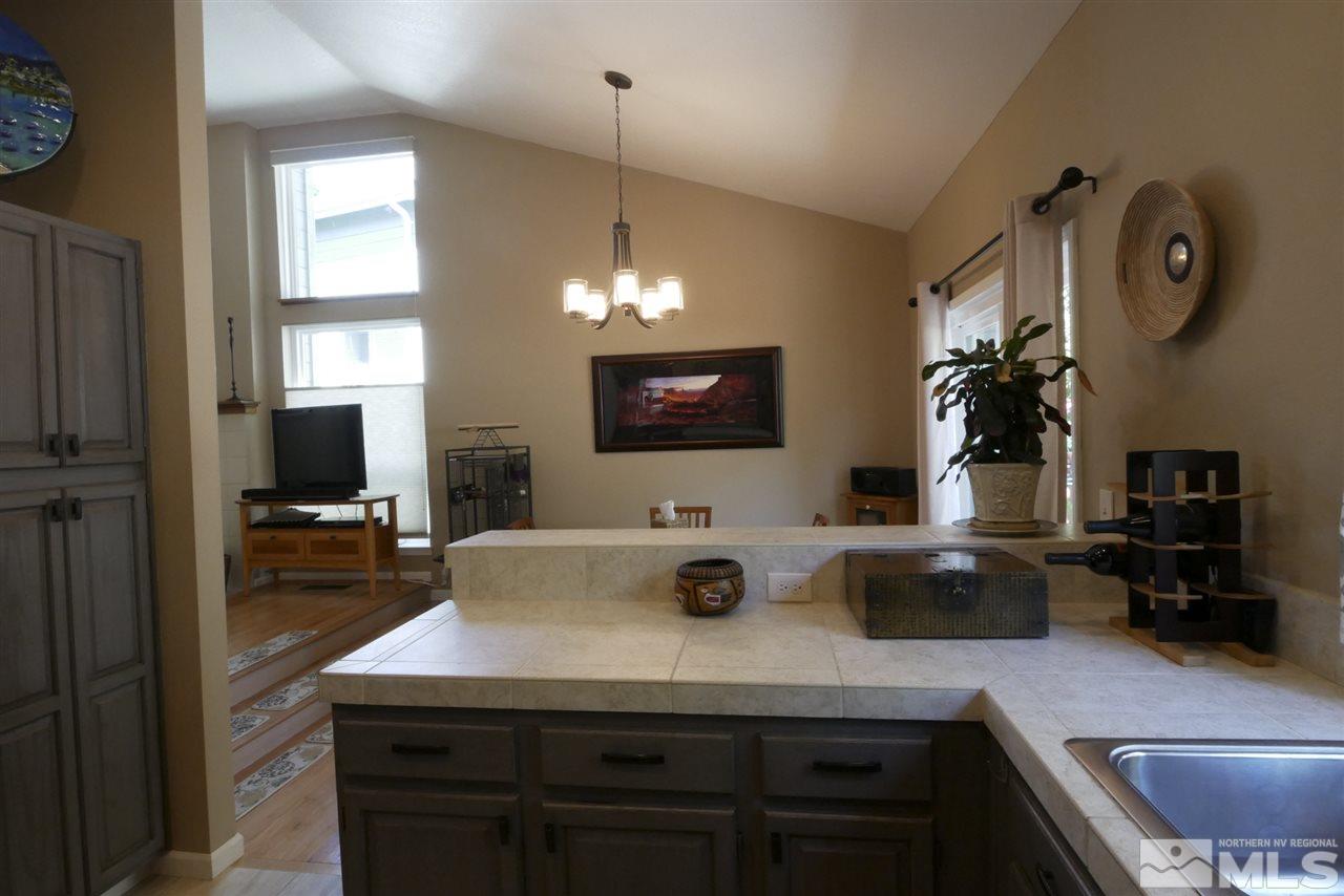 3288 Alum Creek Court Reno, NV 89509 - Photo 3 of 20 a kitchen with a sink dishwasher a dining table and chairs with wooden floor
