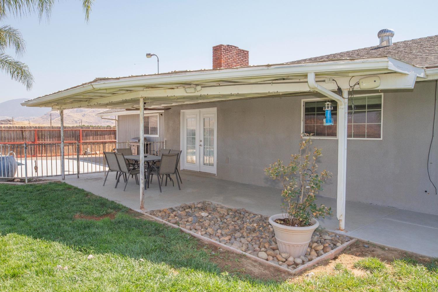 5357 South Hills Valley Road Orange Cove, CA 93646 - Photo 42 of 55 a view of a patio with table and chairs potted plants and floor to ceiling window