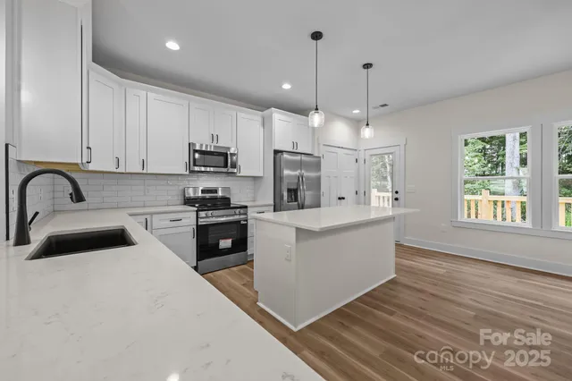 a kitchen with kitchen island granite countertop a sink stainless steel appliances and white cabinets