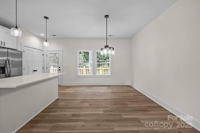 a view of an empty room with window and wooden floor