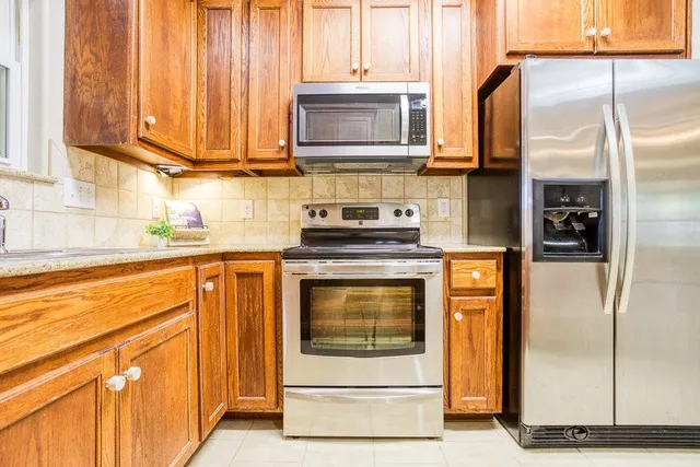 a kitchen with stainless steel appliances granite countertop a refrigerator a stove and a sink with wooden floor