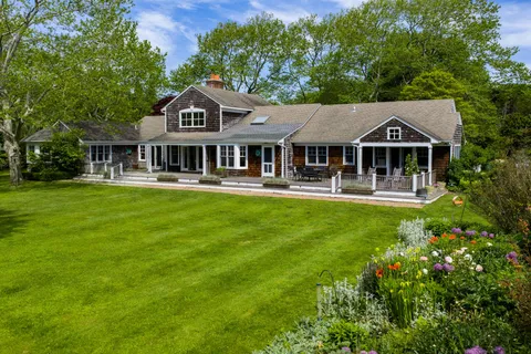 a front view of a house with a garden and trees