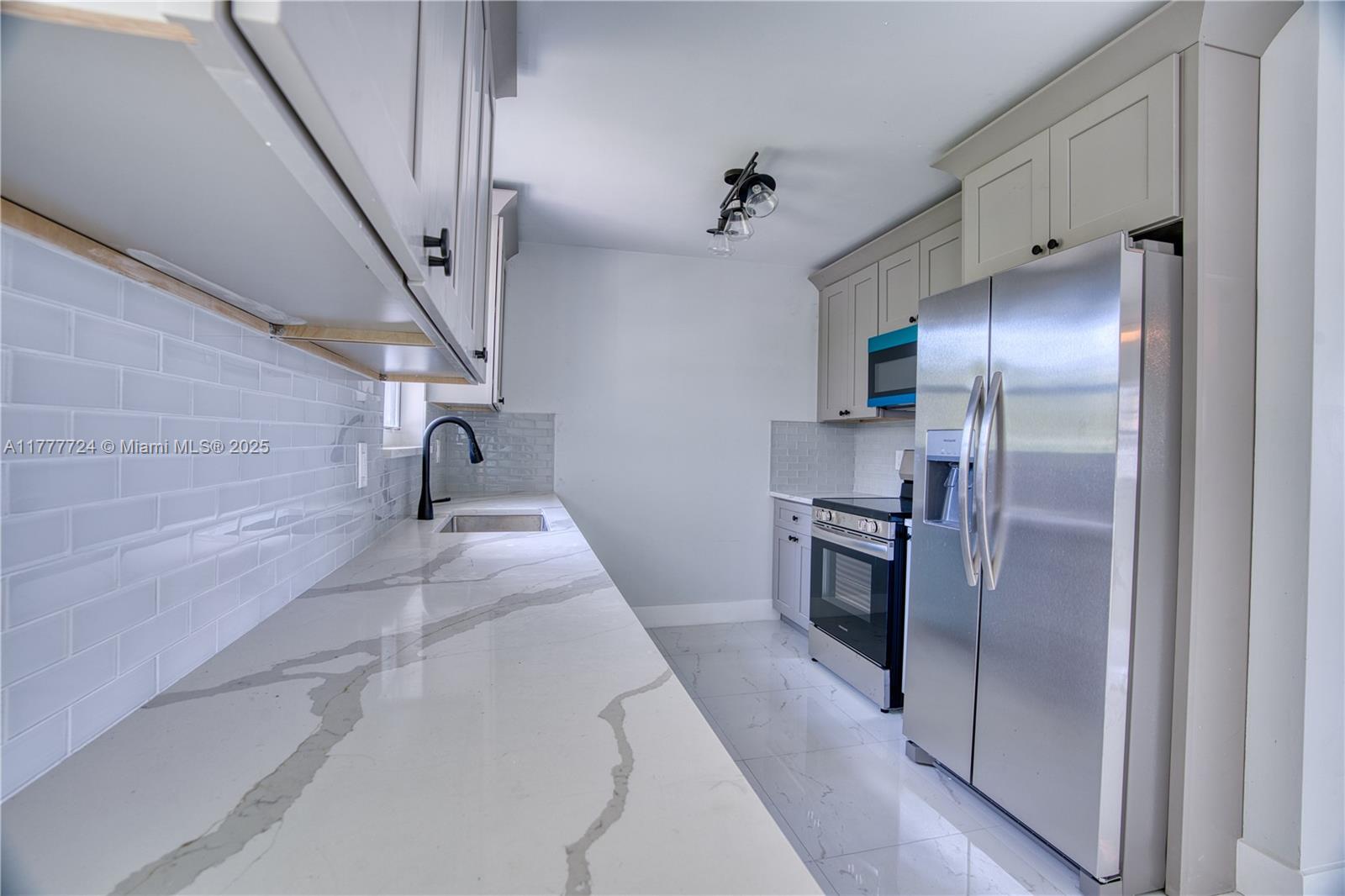 697 Pawnee Street Jupiter, FL 33458 - Photo 12 of 46 a kitchen with stainless steel appliances kitchen island a refrigerator and a stove top oven