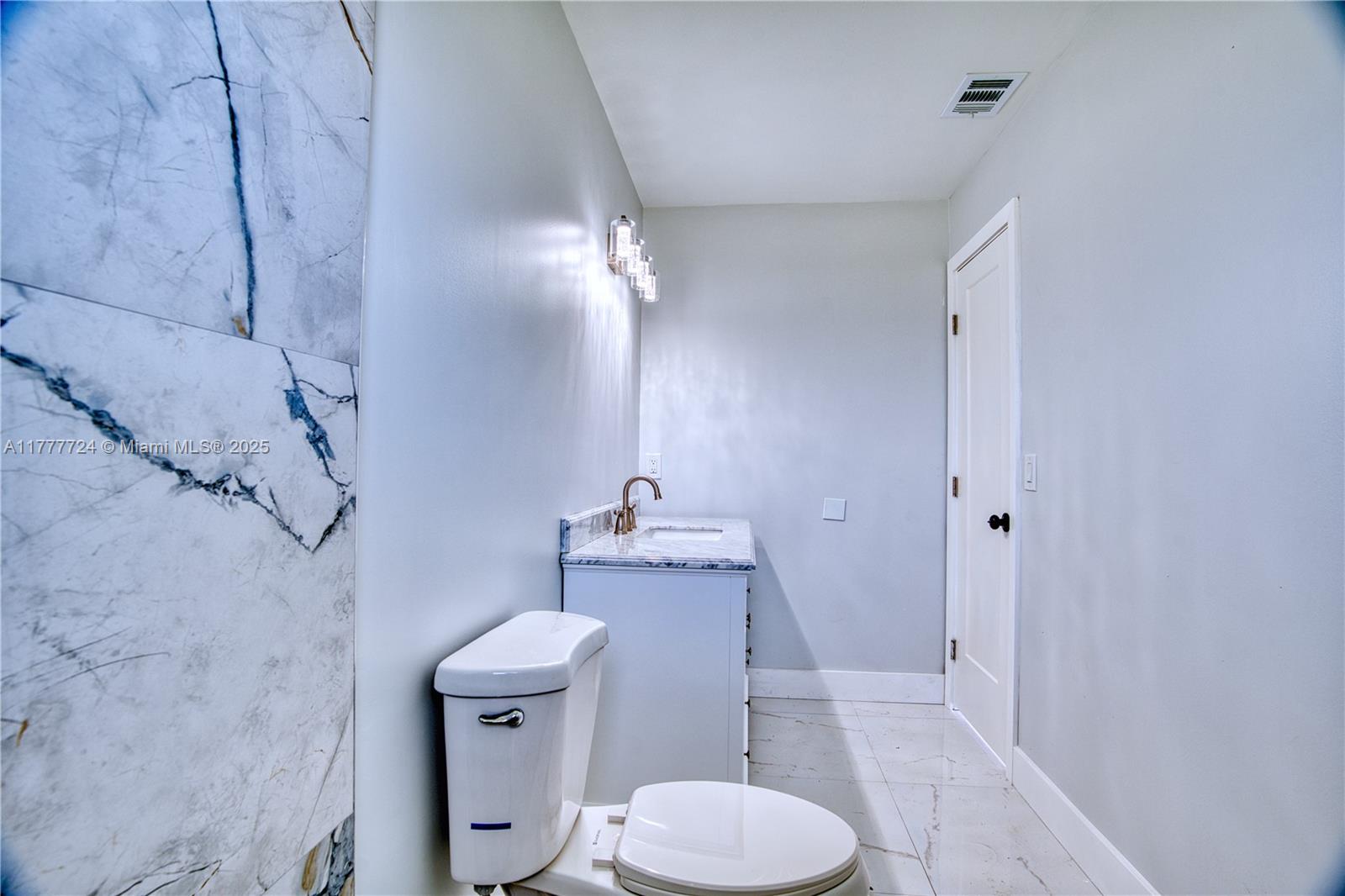 697 Pawnee Street Jupiter, FL 33458 - Photo 21 of 46 a bathroom with a granite countertop toilet a sink and a mirror