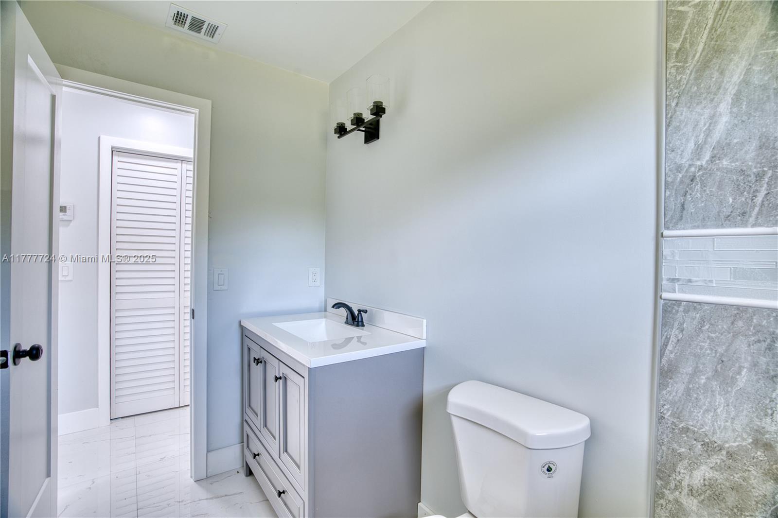 697 Pawnee Street Jupiter, FL 33458 - Photo 26 of 46 a bathroom with a sink a toilet and a mirror