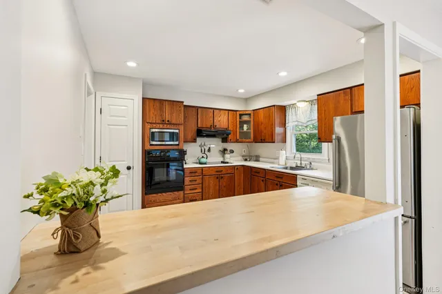 a kitchen with stainless steel appliances granite countertop a refrigerator a sink a stove a oven with wooden cabinets