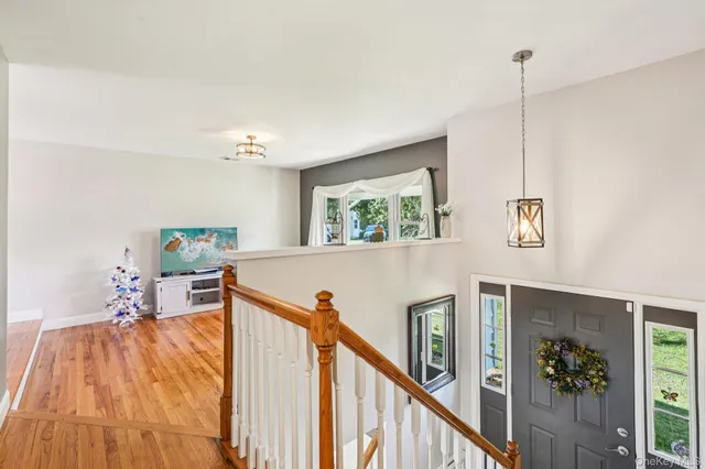 a view of a livingroom with furniture stairs wooden floor and windows