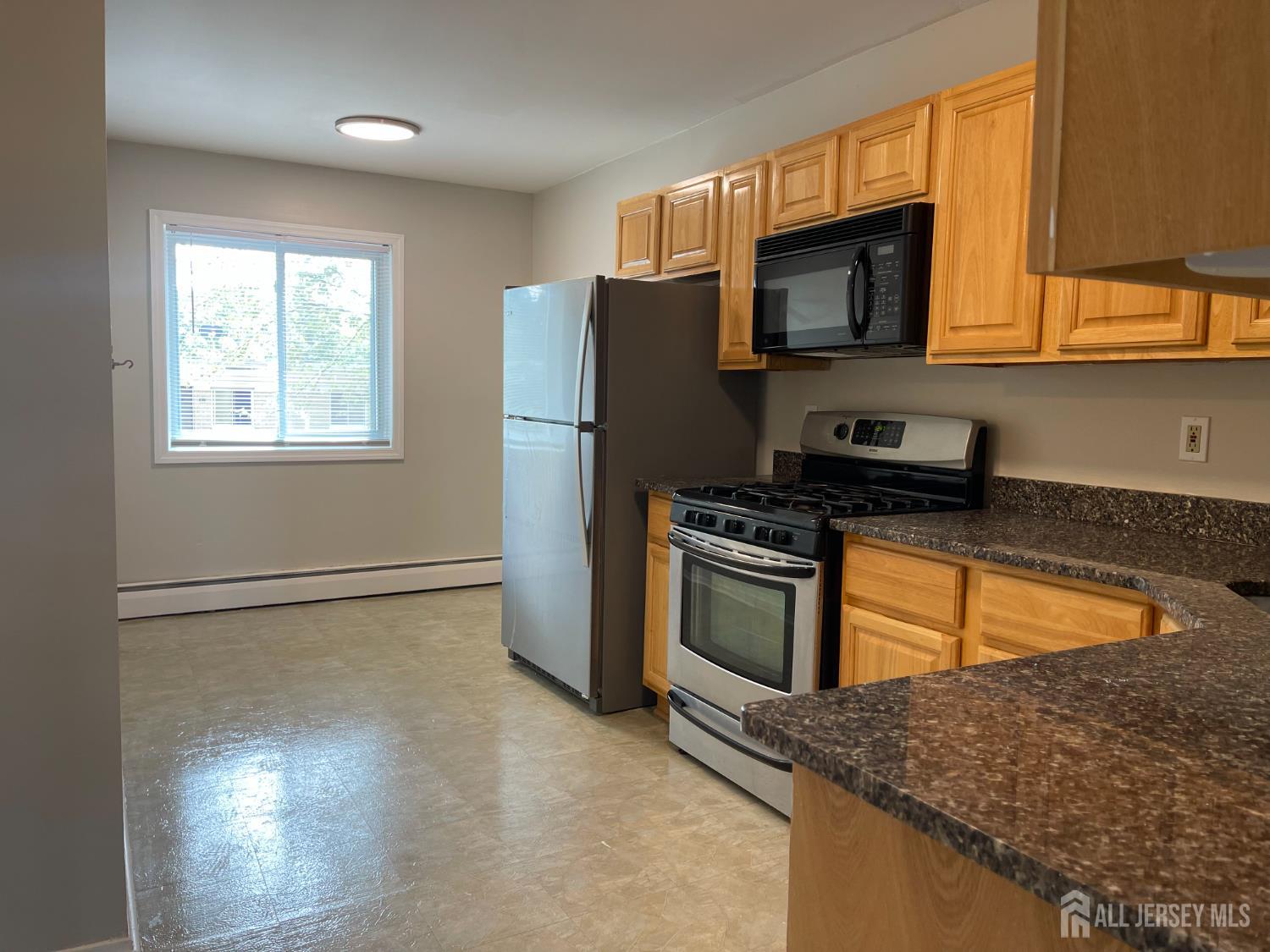 a kitchen with granite countertop a refrigerator and a stove top oven