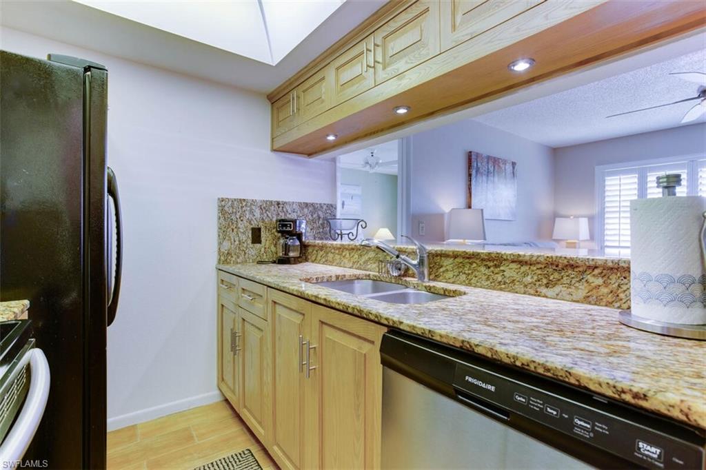 4345 27th Court Southwest, Unit 202 Naples, FL 34116 - Photo 12 of 26 a kitchen with stainless steel appliances granite countertop a sink a stove and a refrigerator