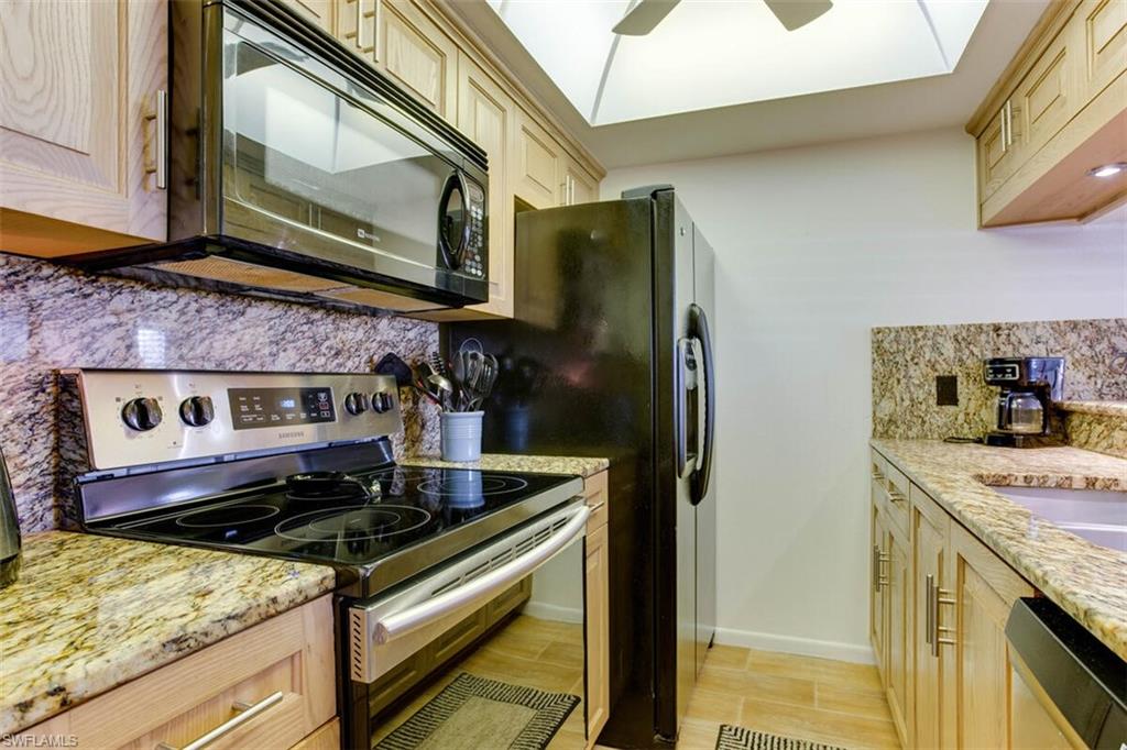 4345 27th Court Southwest, Unit 202 Naples, FL 34116 - Photo 13 of 26 a kitchen with stainless steel appliances granite countertop a stove and a microwave