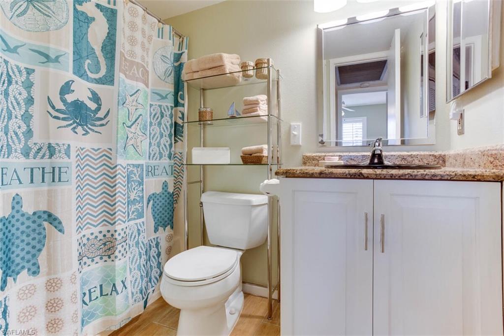 4345 27th Court Southwest, Unit 202 Naples, FL 34116 - Photo 15 of 26 a bathroom with a granite countertop toilet sink and mirror