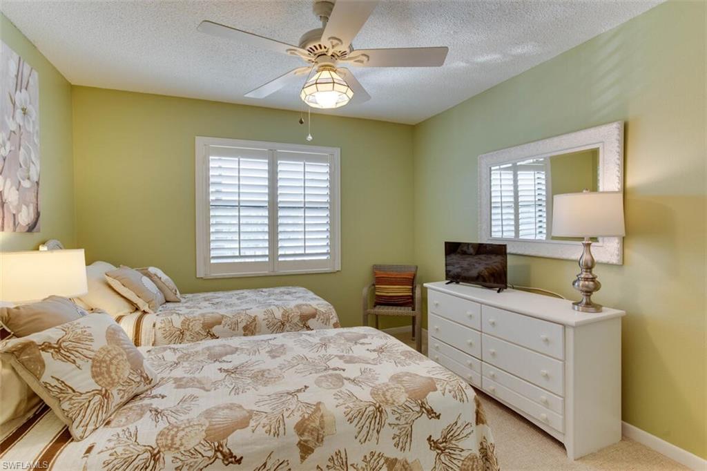 4345 27th Court Southwest, Unit 202 Naples, FL 34116 - Photo 16 of 26 a bedroom with a bed and a chandelier