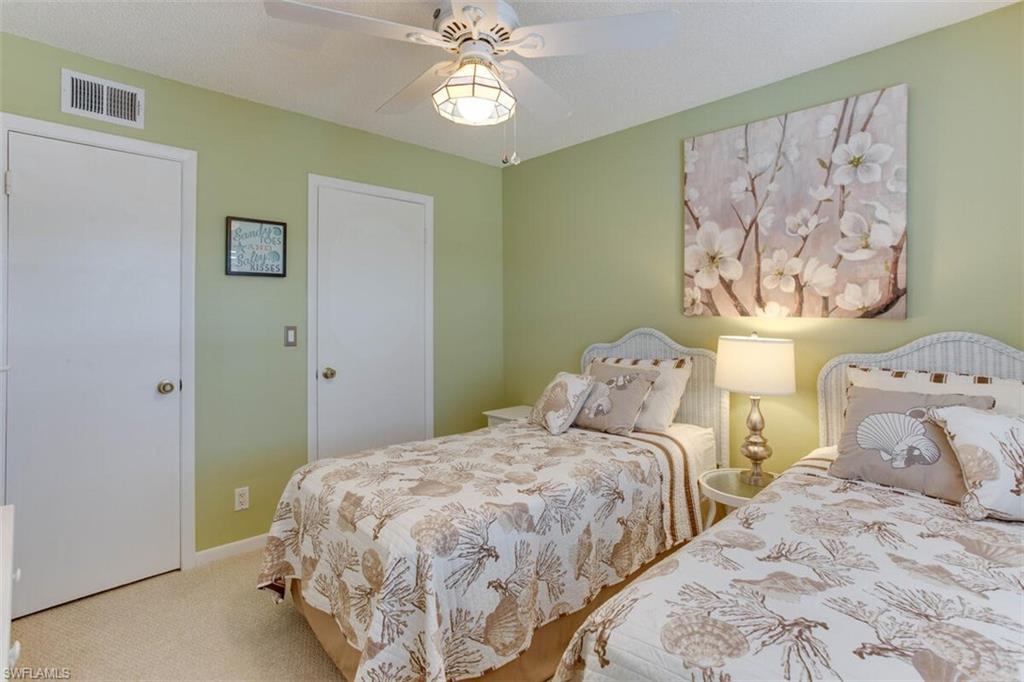 4345 27th Court Southwest, Unit 202 Naples, FL 34116 - Photo 18 of 26 a bedroom with two beds and a chandelier