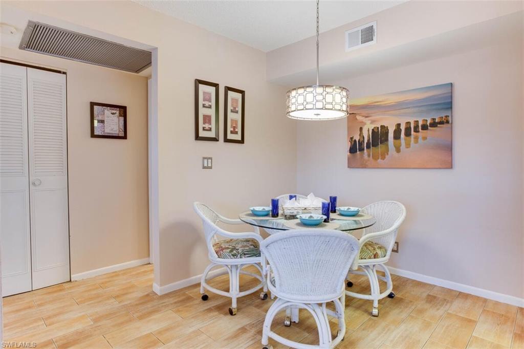 4345 27th Court Southwest, Unit 202 Naples, FL 34116 - Photo 9 of 26 a dining room with furniture and wooden floor