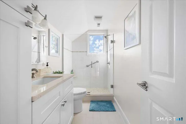 a bathroom with a sink a toilet a mirror and shower