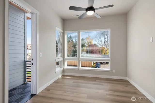 a view of an empty room with a window and wooden floor