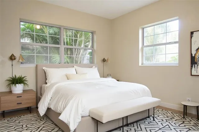 a large white bed sitting in a bedroom next to a window