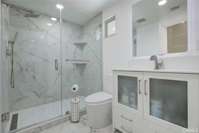 a bathroom with a toilet shower vanity and a sink