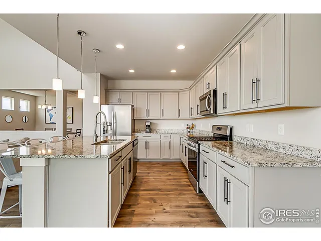 a kitchen with stainless steel appliances granite countertop a stove top oven a refrigerator a sink and dishwasher with white cabinets