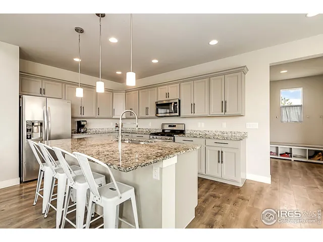 a kitchen with stainless steel appliances kitchen island granite countertop a sink refrigerator and cabinets
