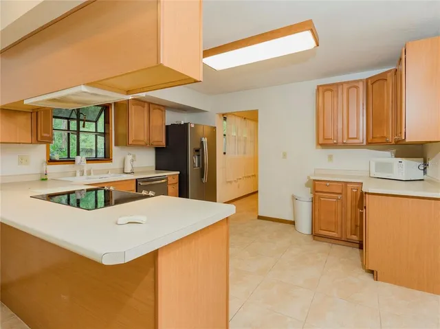 a kitchen with stainless steel appliances kitchen island granite countertop a refrigerator a stove top oven a sink and dishwasher