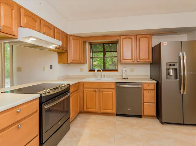 a kitchen with stainless steel appliances granite countertop a refrigerator stove and sink