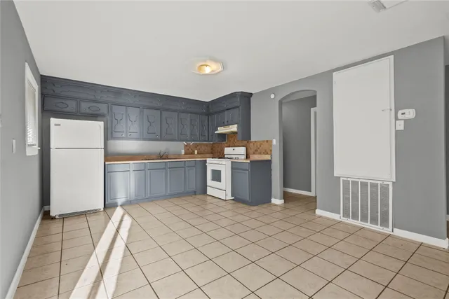 a kitchen with a sink a refrigerator and white cabinets