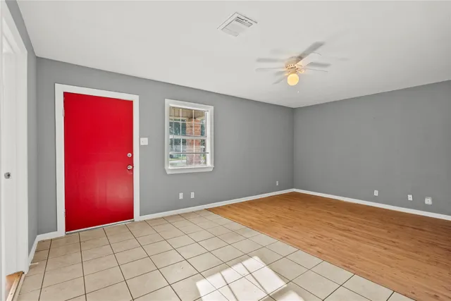 a view of an empty room with window and chandelier fan