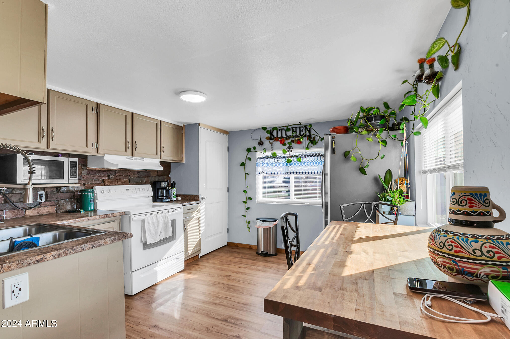 130 East McKellips Road, Unit 48 Mesa, AZ 85201 - Photo 10 of 24 a kitchen with granite countertop a stove a sink dishwasher and white cabinets with wooden floor