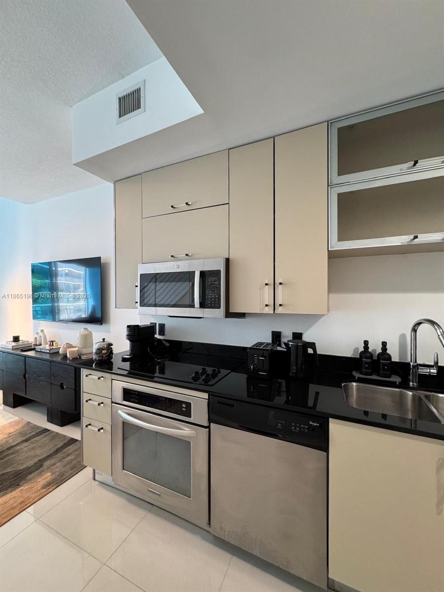 60 Southwest 13th Street, Unit 1406 Miami, FL 33130 - Photo 5 of 19 a kitchen with granite countertop a sink a stove and cabinets