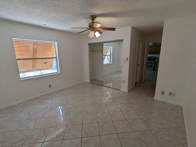 a view of an empty room with a chandelier fan and a window