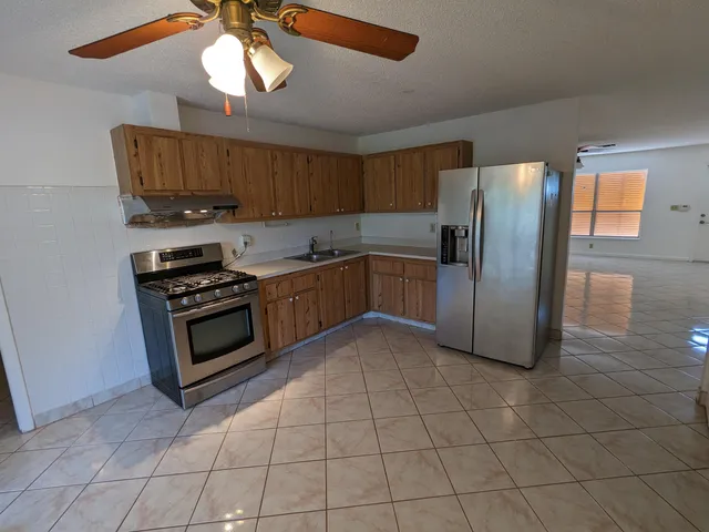 a kitchen with stainless steel appliances granite countertop a refrigerator a stove a sink and a microwave