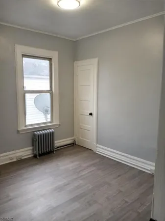 an empty room with wooden floor cabinet and windows