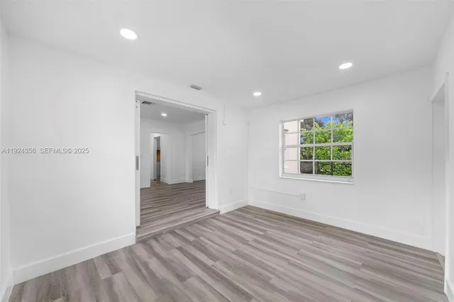 an empty room with wooden floor and a window