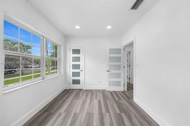 a view of empty room with wooden floor and windows