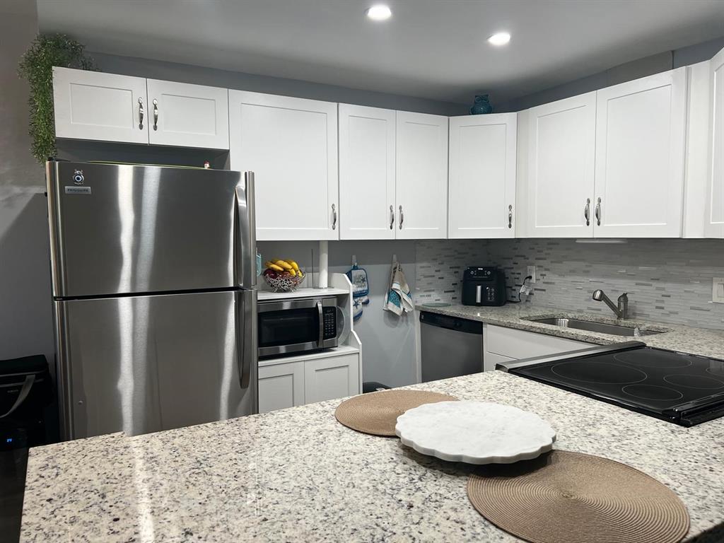 418 Durham, Unit 418 Deerfield Beach, FL 33442 - Photo 2 of 47 a kitchen with stainless steel appliances kitchen island granite countertop a refrigerator a sink a stove and white cabinets